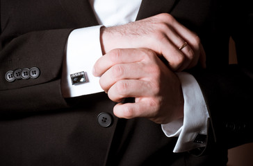 Obraz premium Closeup of a man in black suit correcting a sleeve