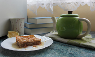 Teakettle, piece of turkish dessert - baklava and books
