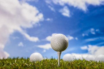 Golf balls, green grass, clouds background