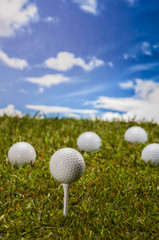Golf balls, green grass, clouds background