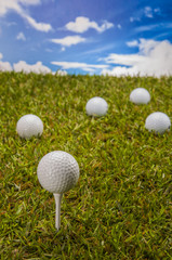 Golf balls, green grass, clouds background