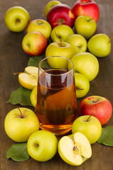 Useful apple juice with apples around on wooden table