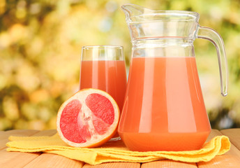 Full glass and jug of grapefruit juice and grapefruits