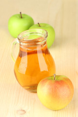 Full jug of apple juice and apple on wooden background