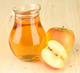 Full jug of apple juice and apple on wooden background