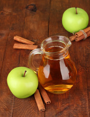 Full jug of apple juice and apple on wooden background