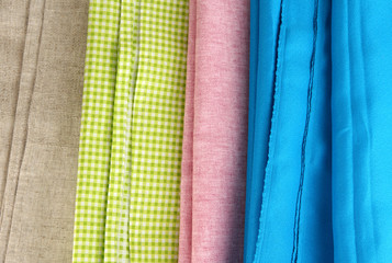 Pile of different fabrics close-up background