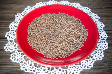 Lentils in the red plate on wood background