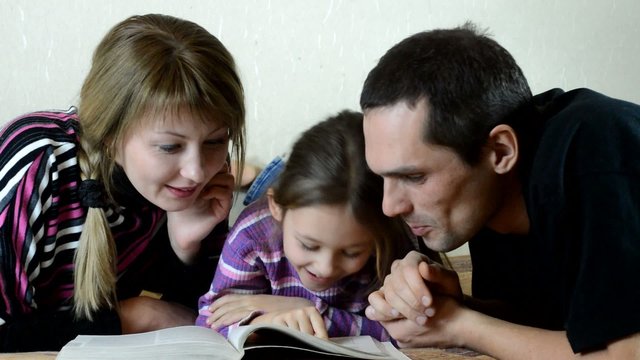 father, mother and daughter reading a book