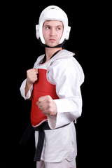Naklejka premium Young man in Taekwondo gear standing against black background