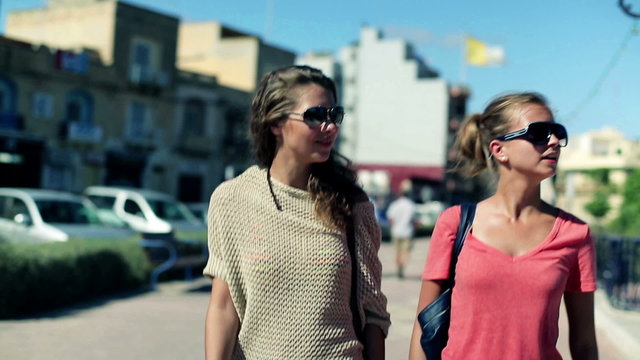 Female friends walking the street and talking