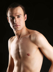 Fototapeta premium Portrait of a naked muscular man, isolated on black background
