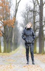 woman wearing black clothes and boots in autumnal alley