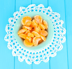 Tasty mandarine's slices on color plate on blue background