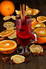 Fragrant mulled wine in glass with spices and oranges around