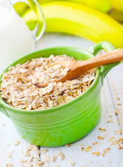 Oat flakes in the green bowl with banana and milk