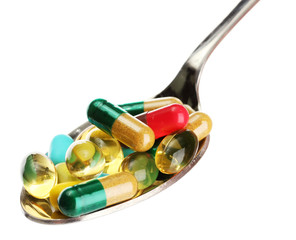 spoon with colorful capsules and pills, isolated on white