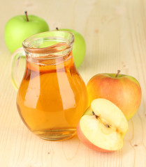Full jug of apple juice and apple on wooden background