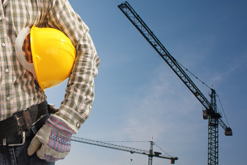builder worker in uniform and helmet operating with tower crane