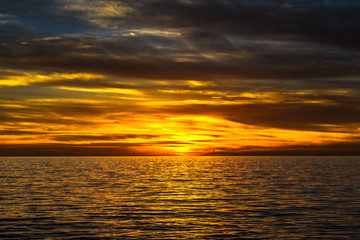 Naklejka na ściany i meble dramatic golden sunset over the ocean