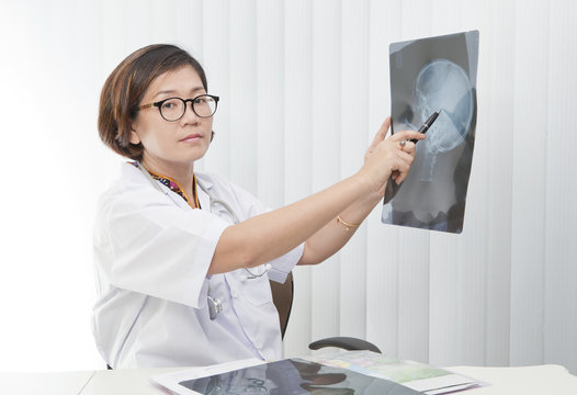 female doctor watching on head skull x-ray film