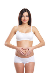 Fototapeta premium A young and happy pregnant brunett standing in white lingerie