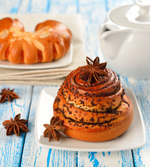 Sweet roll with a poppy on a blue table