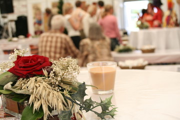 Tisch mit Gesteck und Personen im Hintergrund