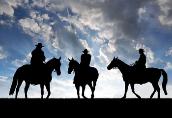 Silhouette cowboys with horses in the sunset