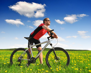biker with the mountain bike in the dandelion field