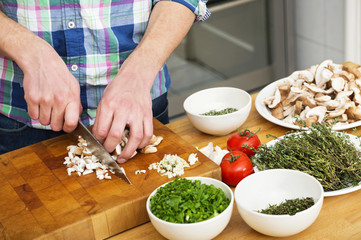 Man Chopping Mushrooms With Vegetables On Counter