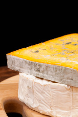 Various types of cheese on wooden table and black background
