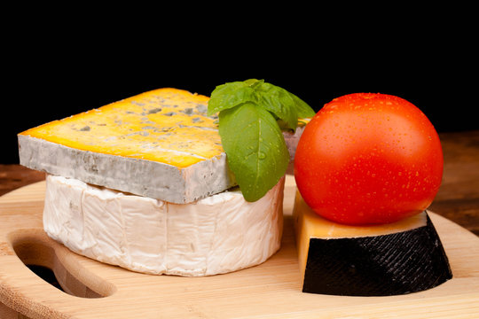 Various types of cheese on wooden table and black background