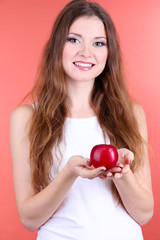 Beautiful woman with apple on pink background