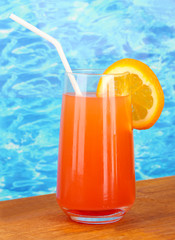 Glass of orange cocktail on blue background