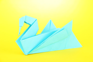 Origami swan on yellow background.