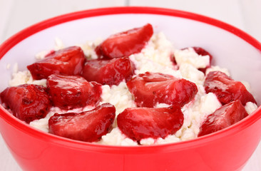 Cottage cheese in red bowl with sliced strawberries