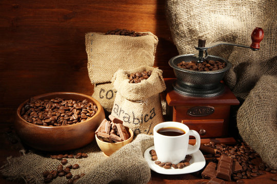 Coffee grinder and cup of coffee on brown wooden background