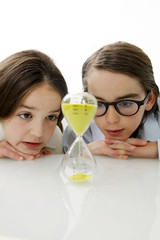Kinder beobachten den Zeitablauf einer Sanduhr