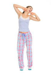 Full length portrait of young woman in pajamas stretching 