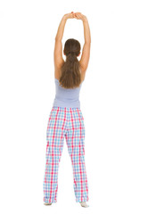 Full length portrait of young woman in pajamas stretching