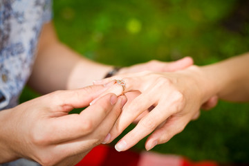 a hand of a man putting a ring on a girl's finger