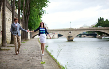 Obraz premium Couple is walking by the Seine embankment in Paris