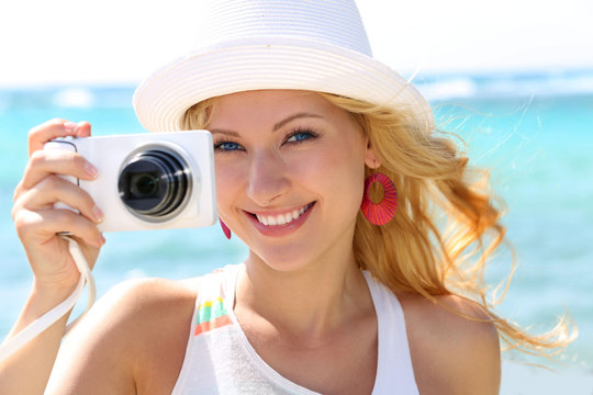 Cheerful girl talking pictures with digital camera