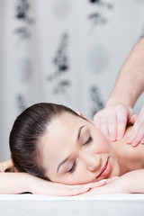 Obraz na płótnie Canvas Woman with closed eyes receives body massage at spa salon