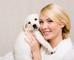 Woman keeping white labrador puppy near her face