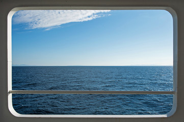Ship window with a relaxing seascape and blue sky view.