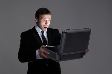Surprised businessman opening his briefcase