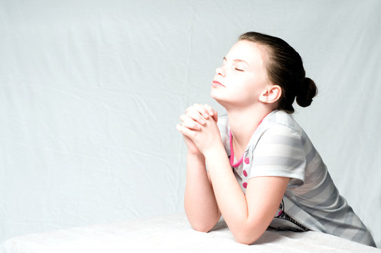 An image of a young girl praying on white background