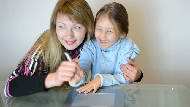 happy mother and daughter drawing on the graphics tablet